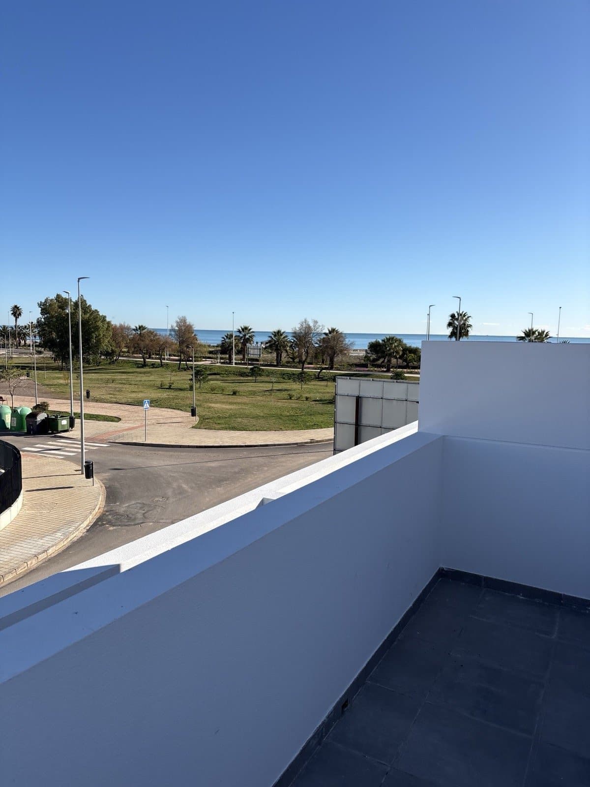 Uitzicht vanaf een Spaans terras op de palmenboulevard en de Middellandse Zee